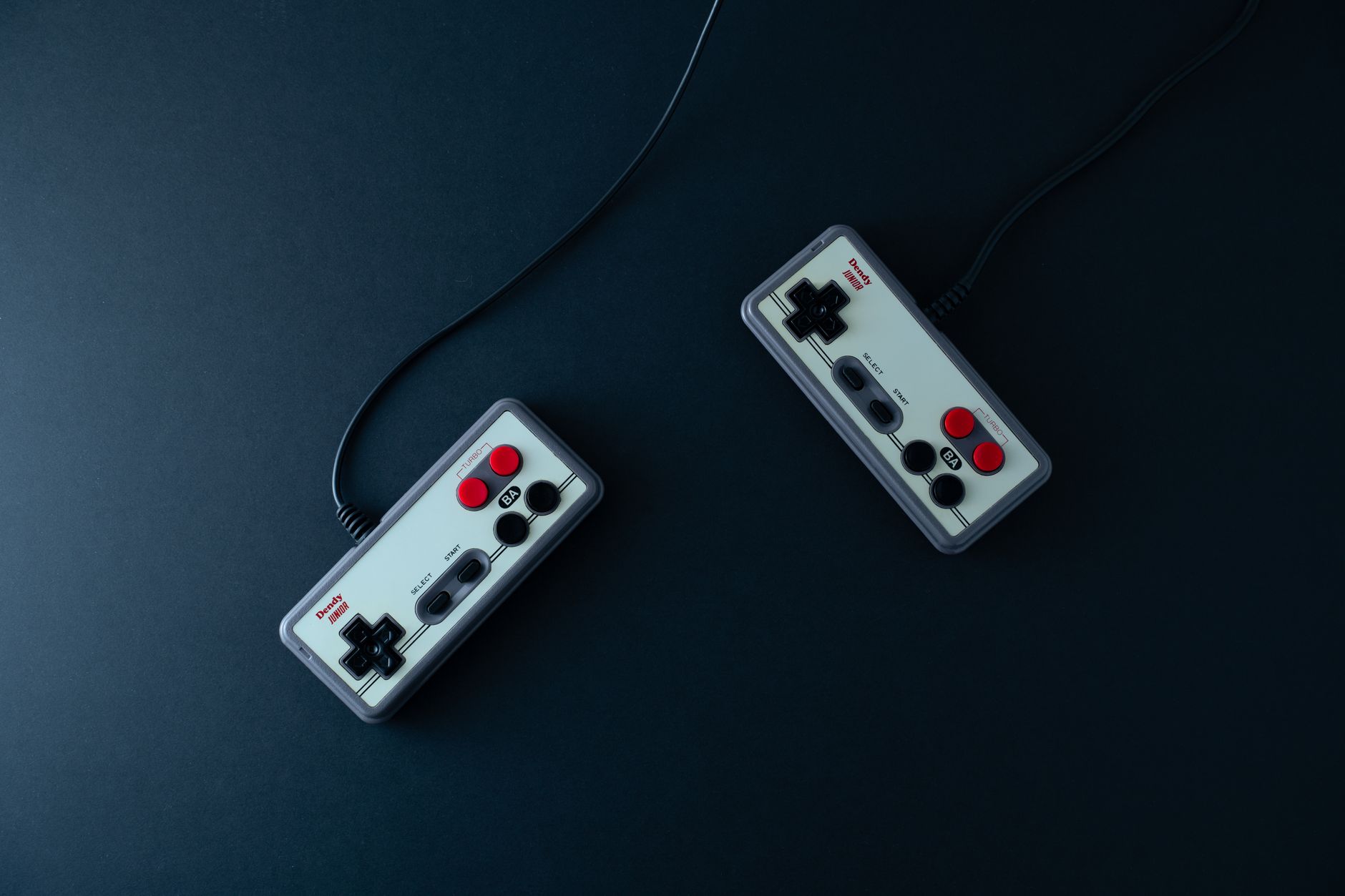 Top view of two retro gaming controllers on a minimalist dark background.