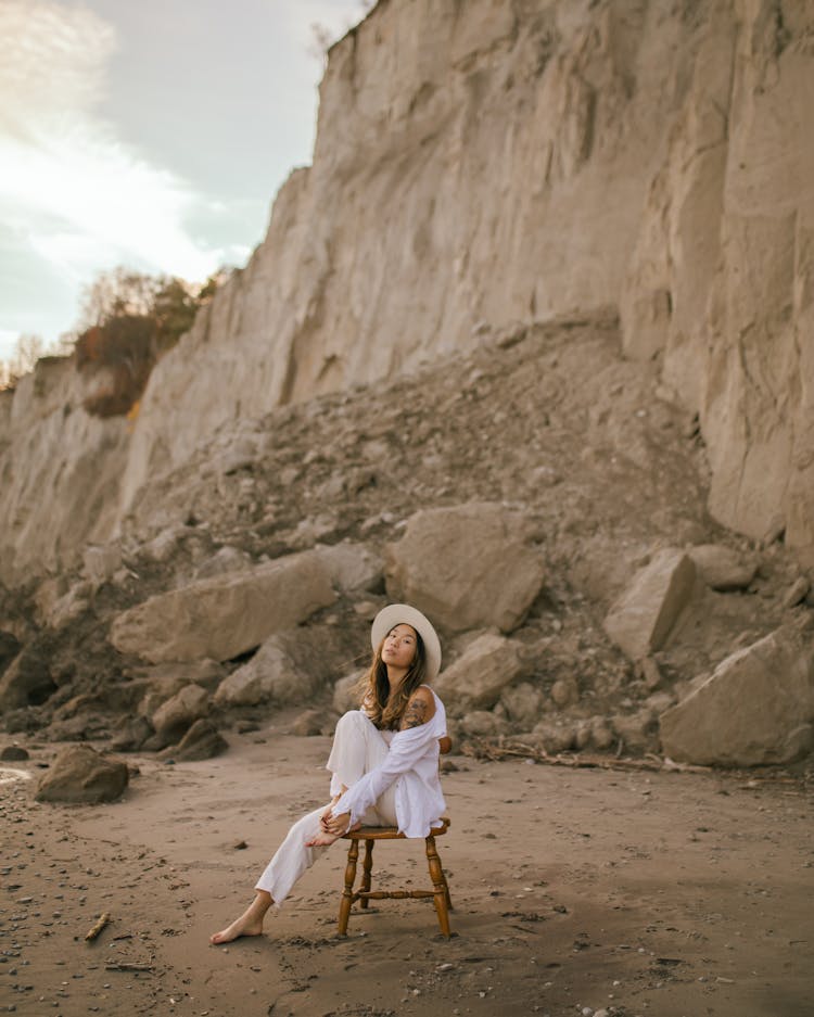 Woman Sitting On Chair On Beach Hugging Leg