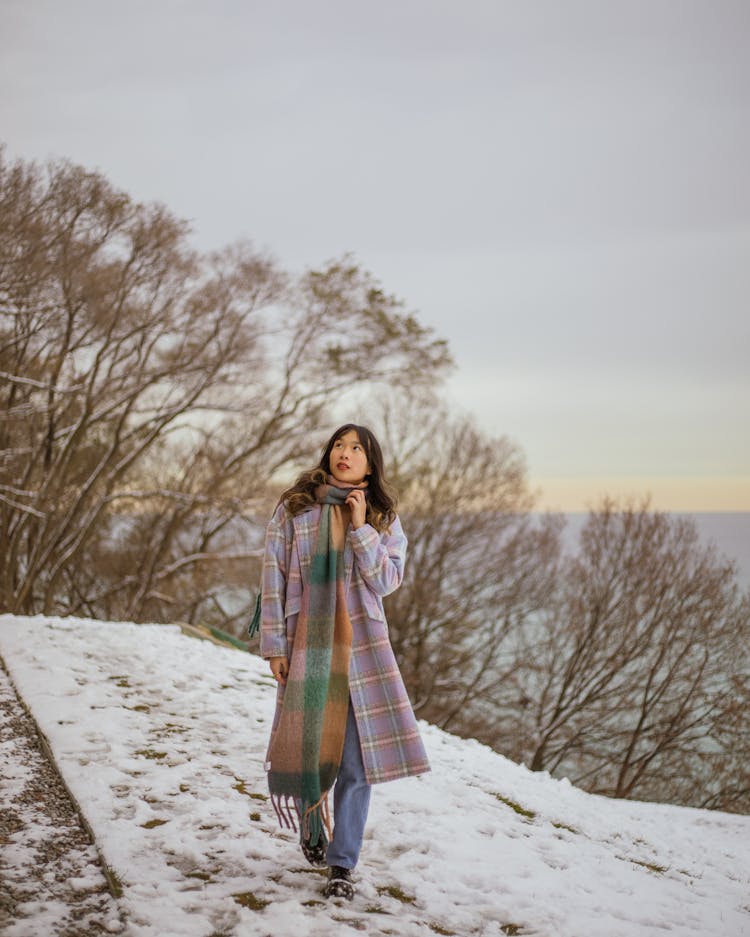 Woman In Long Coat And Scarf Walking On Snow