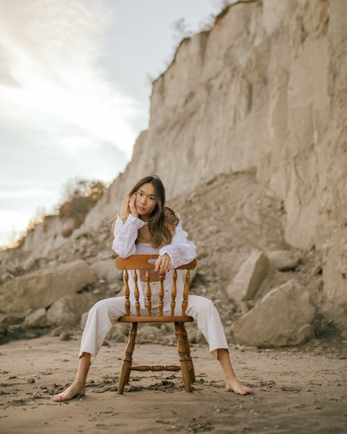 Woman Sitting Backwards on Chair on Beach