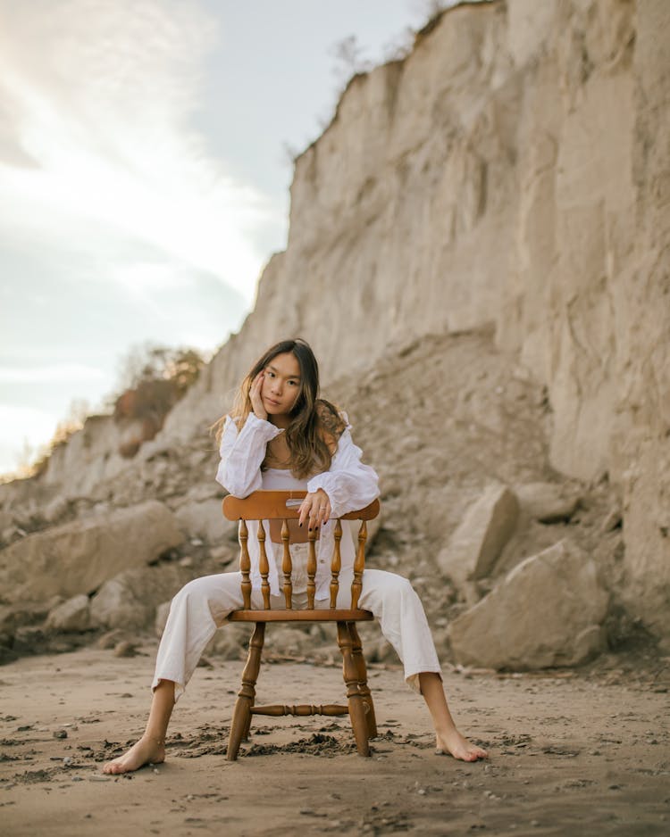 Woman Sitting Backwards On Chair On Beach