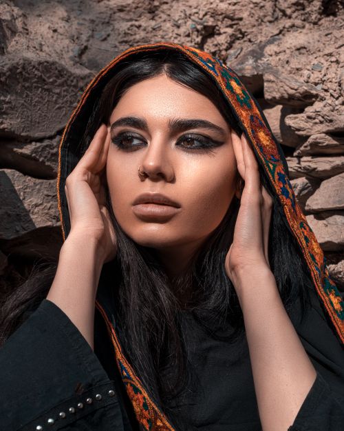 Free Striking portrait of a woman with a colorful headscarf, showcasing bold makeup and a contemplative pose. Stock Photo