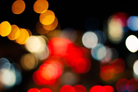 Colorful out-of-focus bokeh lights create a vibrant abstract pattern with red, yellow, and white hues.