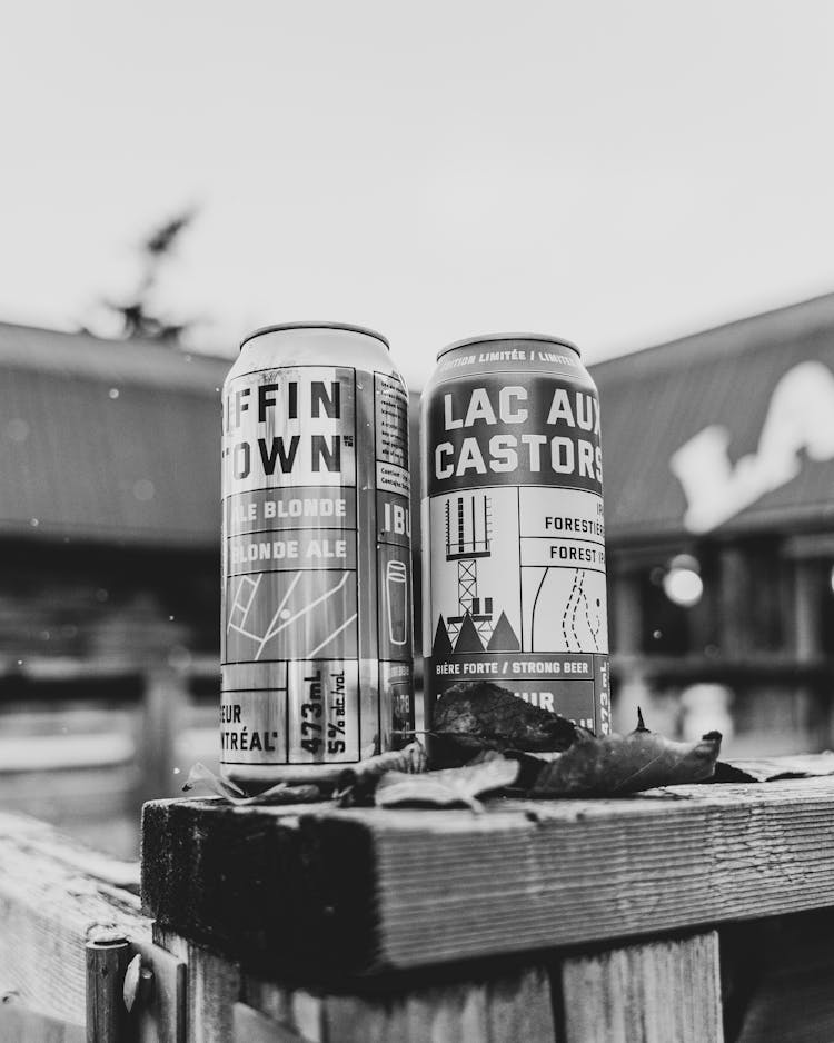 Close-up Of Beer Cans Standing On A Wooden Board Outside 