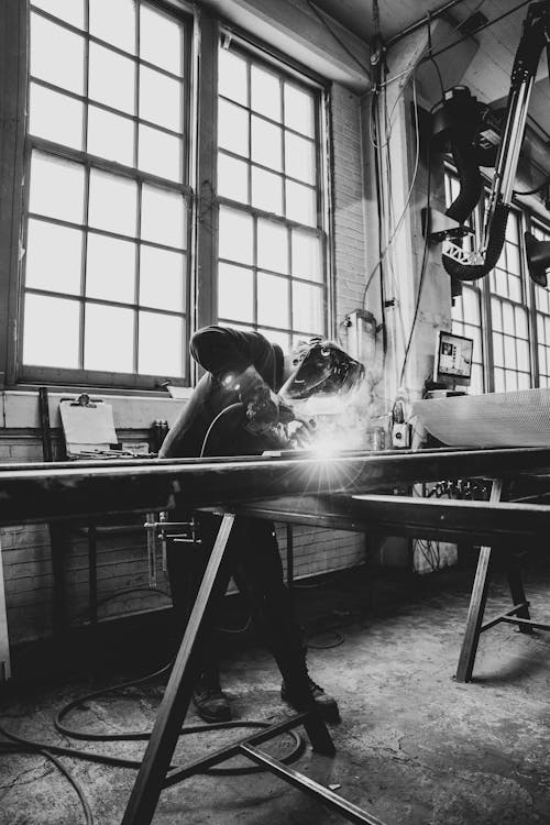 Grayscale Photo of Man Doing Metal Works