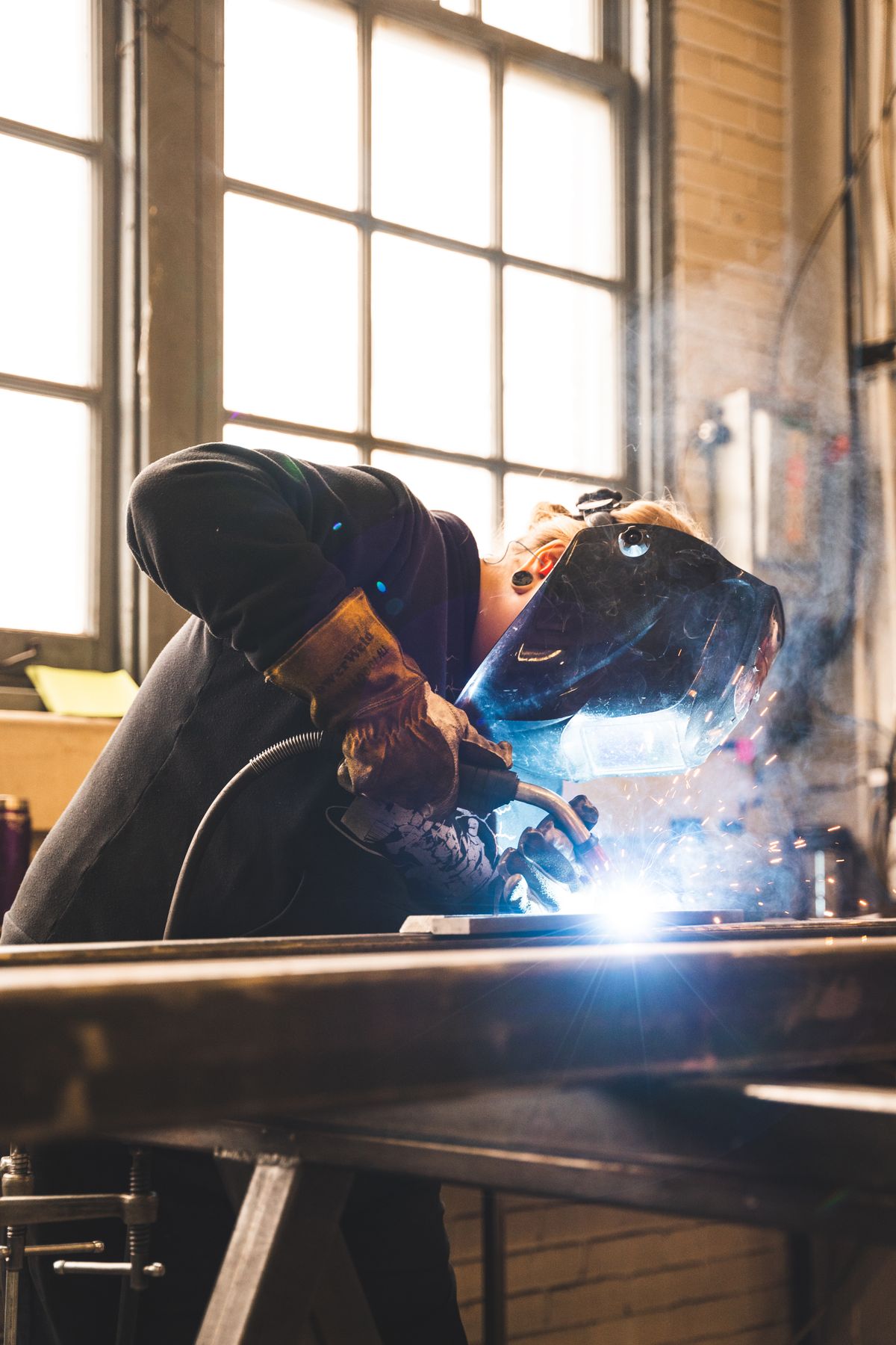 Worker in protective gear emitting sparks in an industrial setting