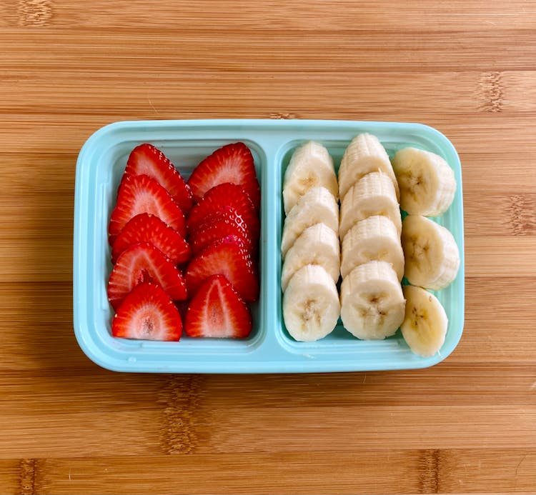 Sliced Strawberries And Bananas On A Plastic Container