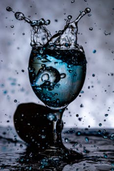 Dramatic close-up of splashing water in a wine glass showcasing dynamic motion.