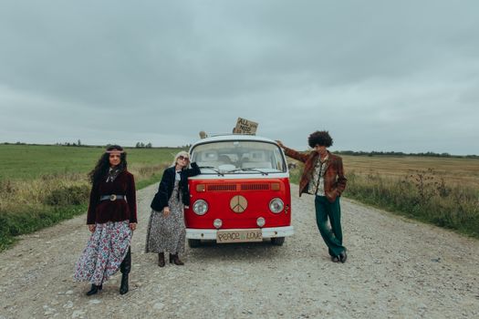 Three people enjoy a retro road trip with a vintage van, radiating hippie vibes and freedom.
