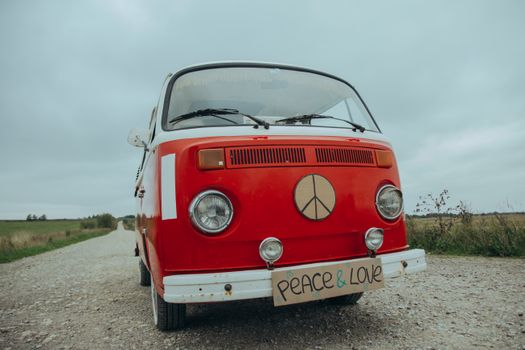 A classic red van with peace sign symbolizing love on a rural gravel road.