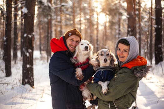 Happy couple with dogs in winter forest, enjoying snow and sunlight.