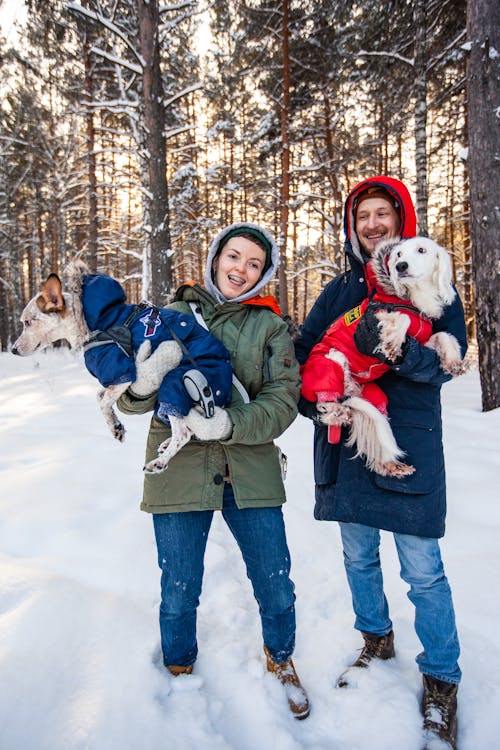 Man and Woman Wearing Jacket Carrying Dogs