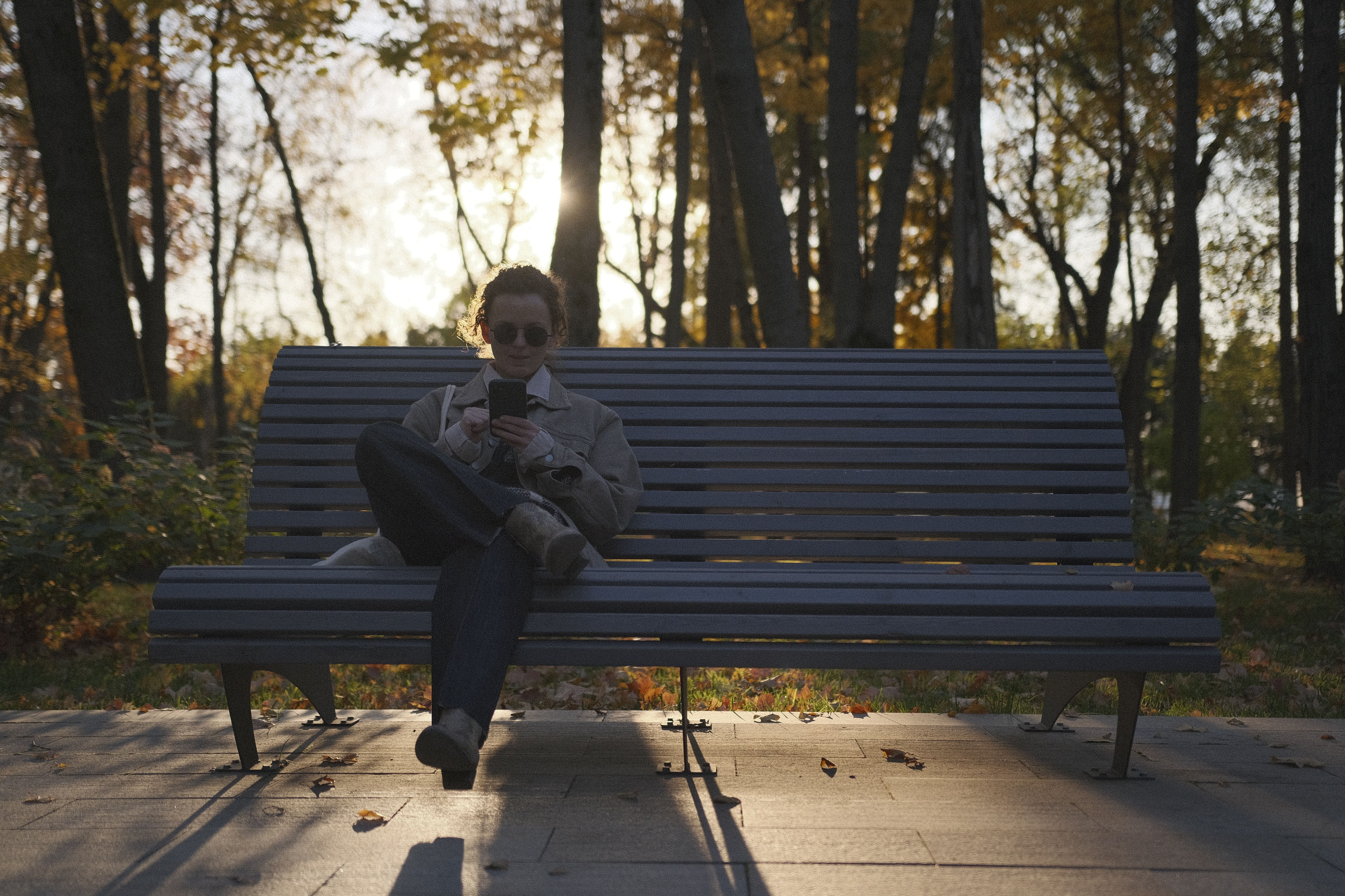 Person sitting on a park bench looking at a sunset without a phone in hand