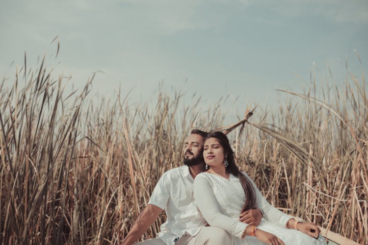 Couple Sitting In Grass In Countryside