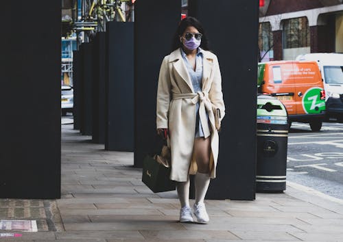 Woman in Brown Coat with Face Mask Walking on Sidewalk