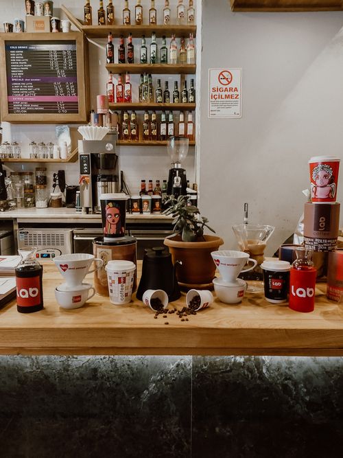 Free Inviting cafe scene featuring coffee brewing tools, mugs, and bottles on a wooden counter. Stock Photo