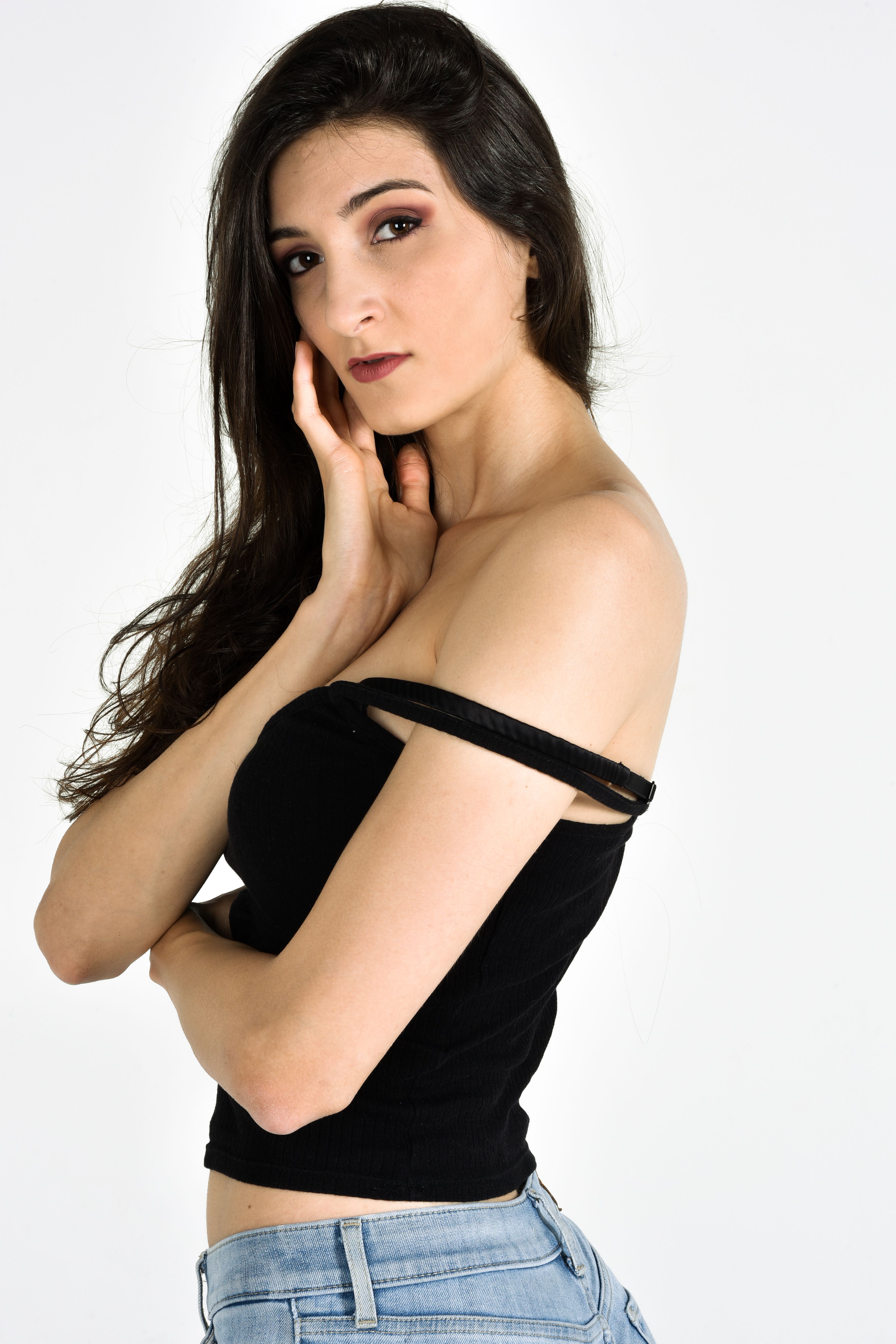 Portrait of a thoughtful woman in a stylish black tank top posing against a white background.