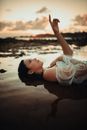 Black Haired Woman Lying on Back and Pointing up