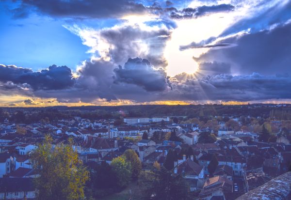Rayons de soleil perçant les nuages d'orage au-dessus des toits au coucher du soleil
