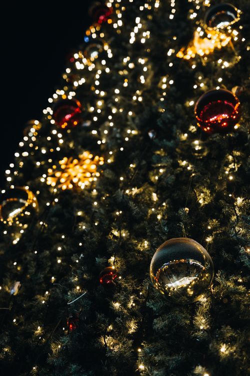 Free Close-up of a decorated Christmas tree with glowing lights and ornaments, perfect for holiday themes. Stock Photo