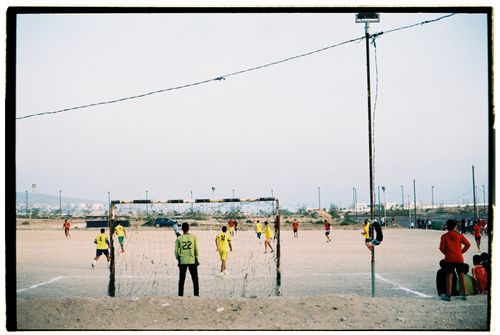 Free Players engaged in a soccer match on a dusty field in Morocco with scattered spectators. Stock Photo