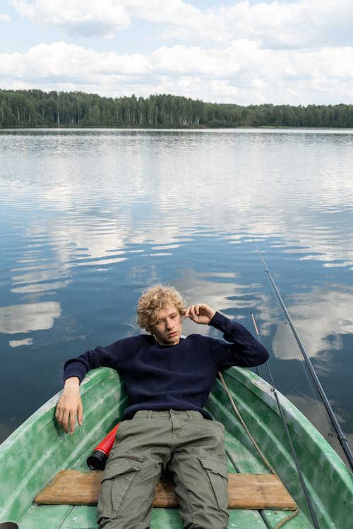 Free Teenage Boy Resting in Boat Floating on Lake Stock Photo