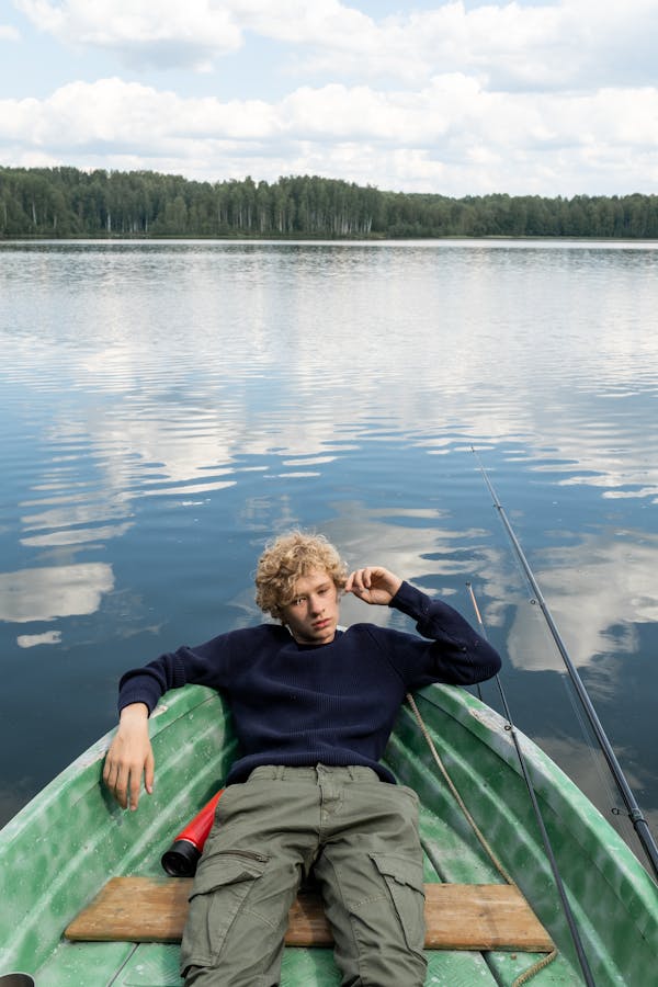 Teenage Boy Resting in Boat Floating on Lake