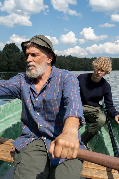 Free Bearded grandfather and grandson rowing a boat on a sunny day at the lake. Stock Photo