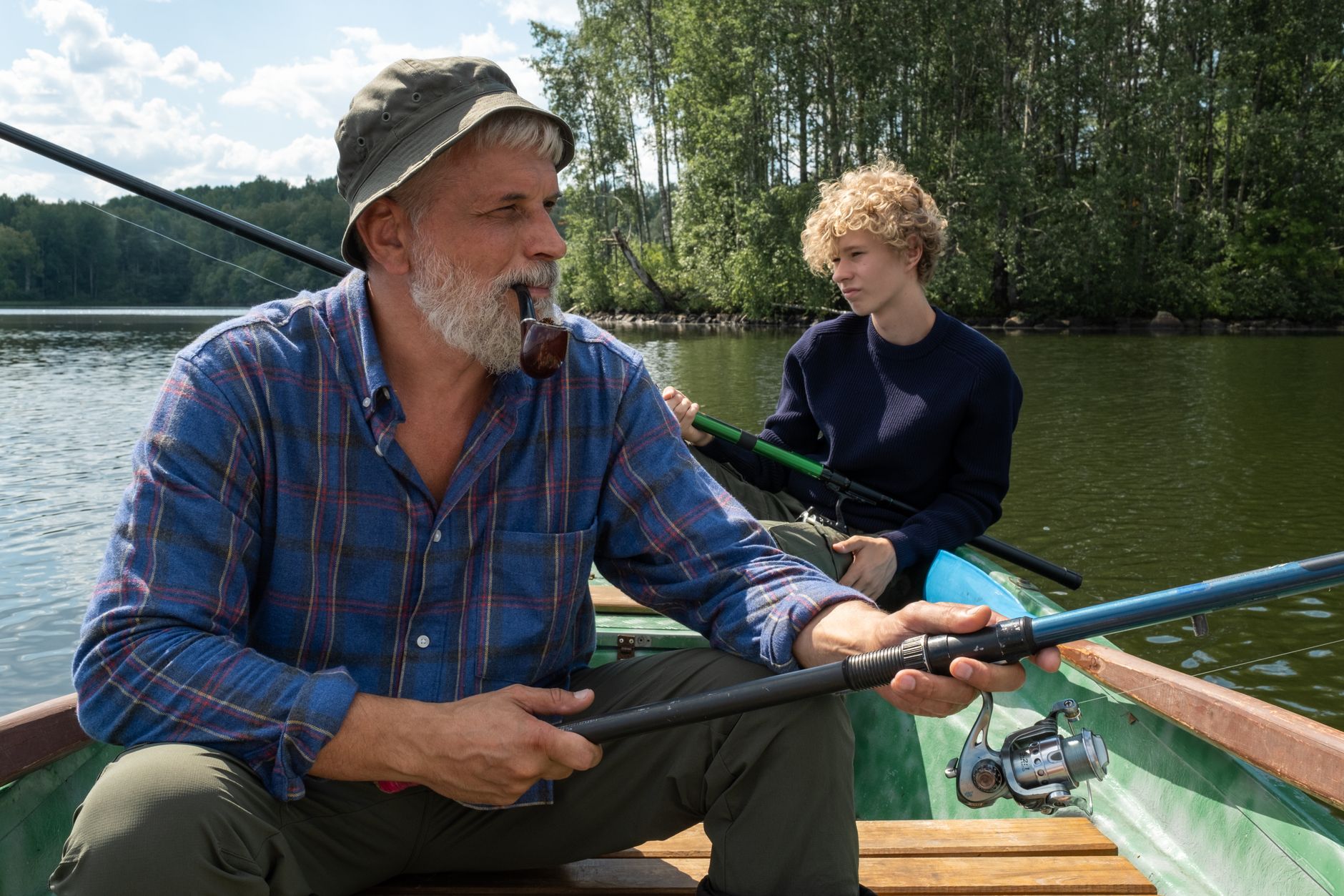A grandfather and grandson share a bonding moment fishing on a serene lake.