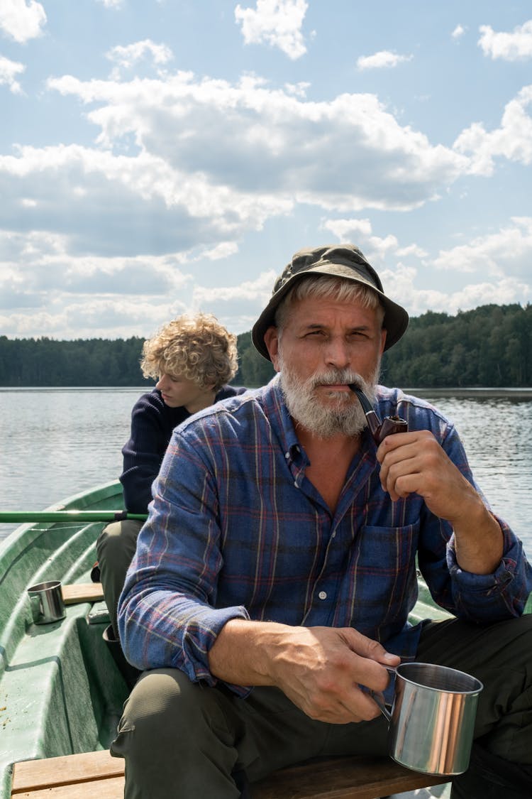 Grandfather Smoking Pipe And Grandson Paddling On Boat Ride