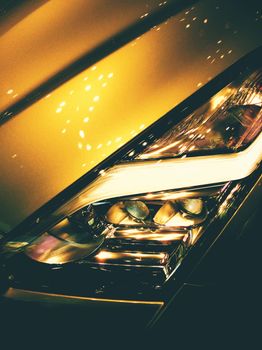 Artistic shot of a car's headlight with dramatic lighting effect at night.