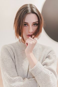 Elegant woman with brown hair posing in a modern studio setting.