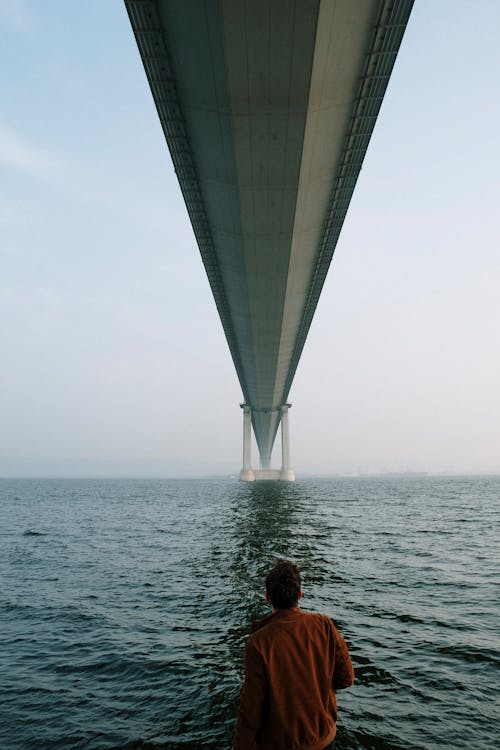 Man Standing Under a Bridge on Sea 
