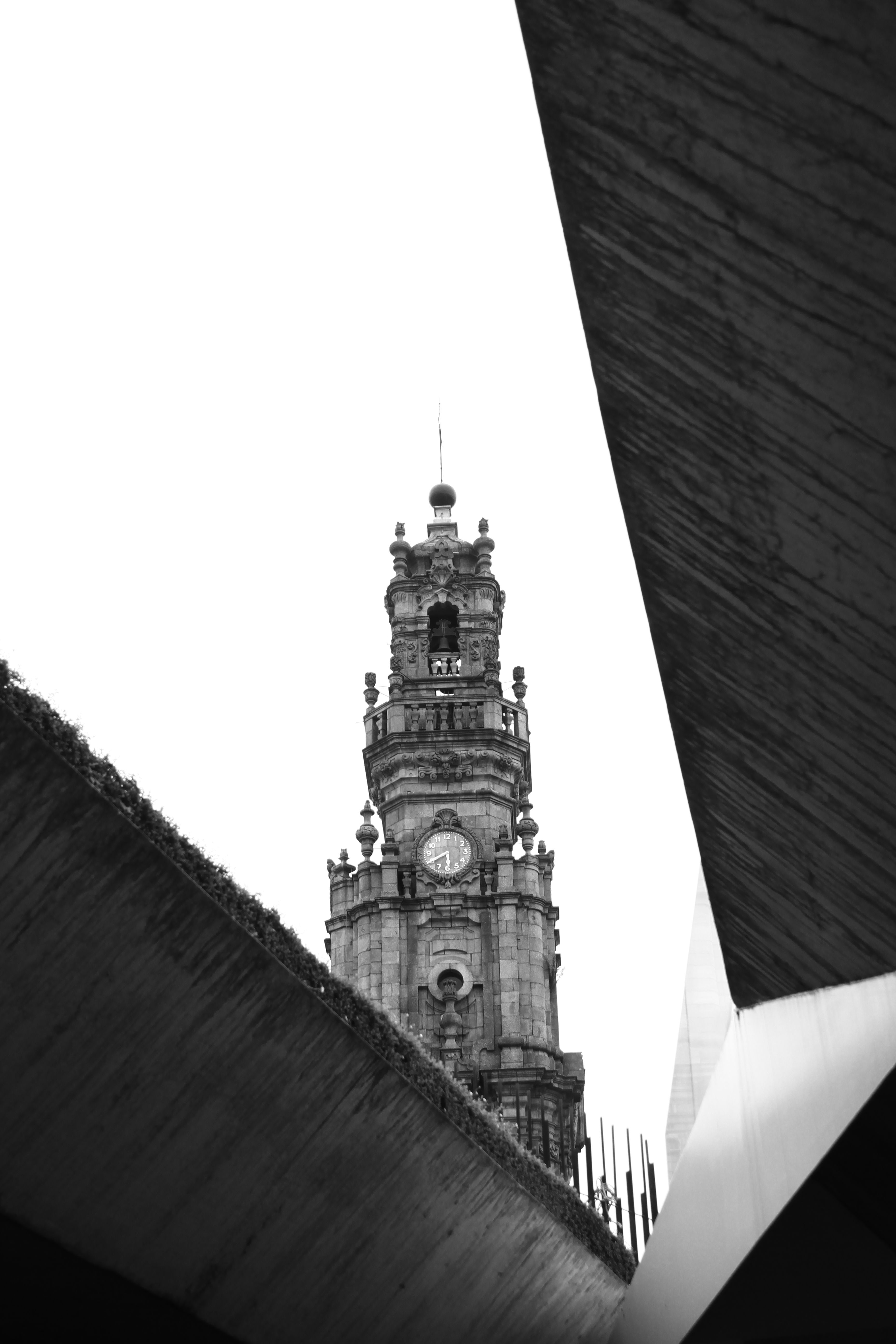 A historic clock tower framed by abstract modern architecture in black and white.