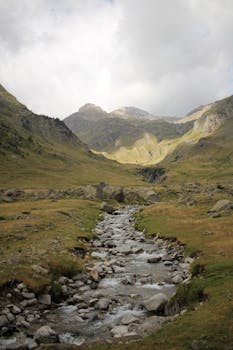 Explore a serene mountain valley with a flowing stream, perfect for nature lovers.