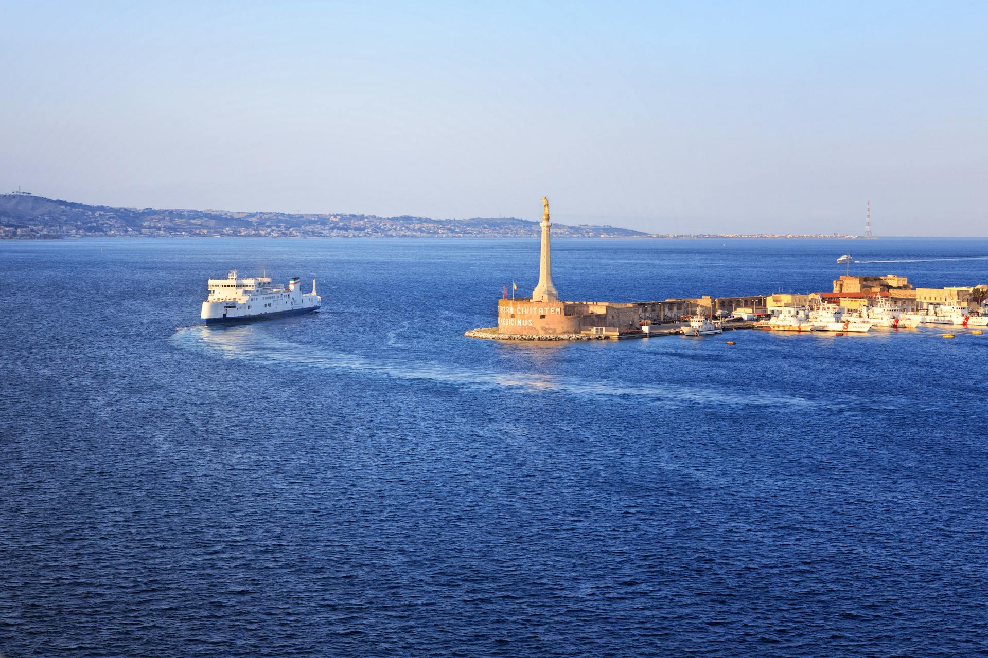 Stunning aerial view of Messina Harbor featuring a cruise ship near a historic monument.