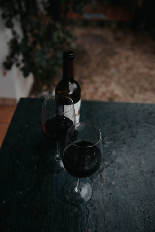 Free Two Glasses of Wine Near a Bottle of Wine Stock Photo