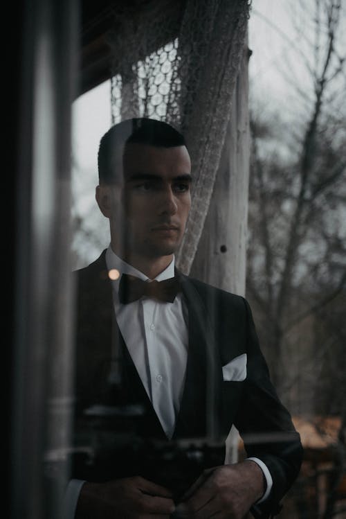 A Man in Black Suit Looking at the Glass