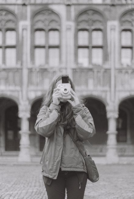 Black-and-white photo of a woman using a camera at a historic site in Liège, Belgium.