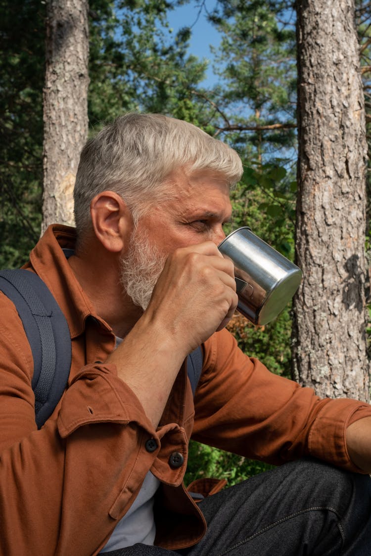 Senior Adult Man Drinking In A Forest From A Tin Cup