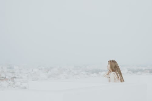 Free Woman in White Dress Sitting on White Snow Covered Ground Stock Photo
