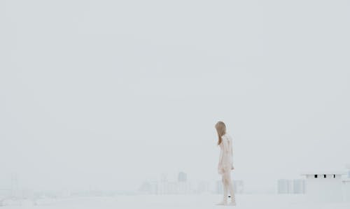 Woman in Beige Dress Walking Barefoot on Rooftop