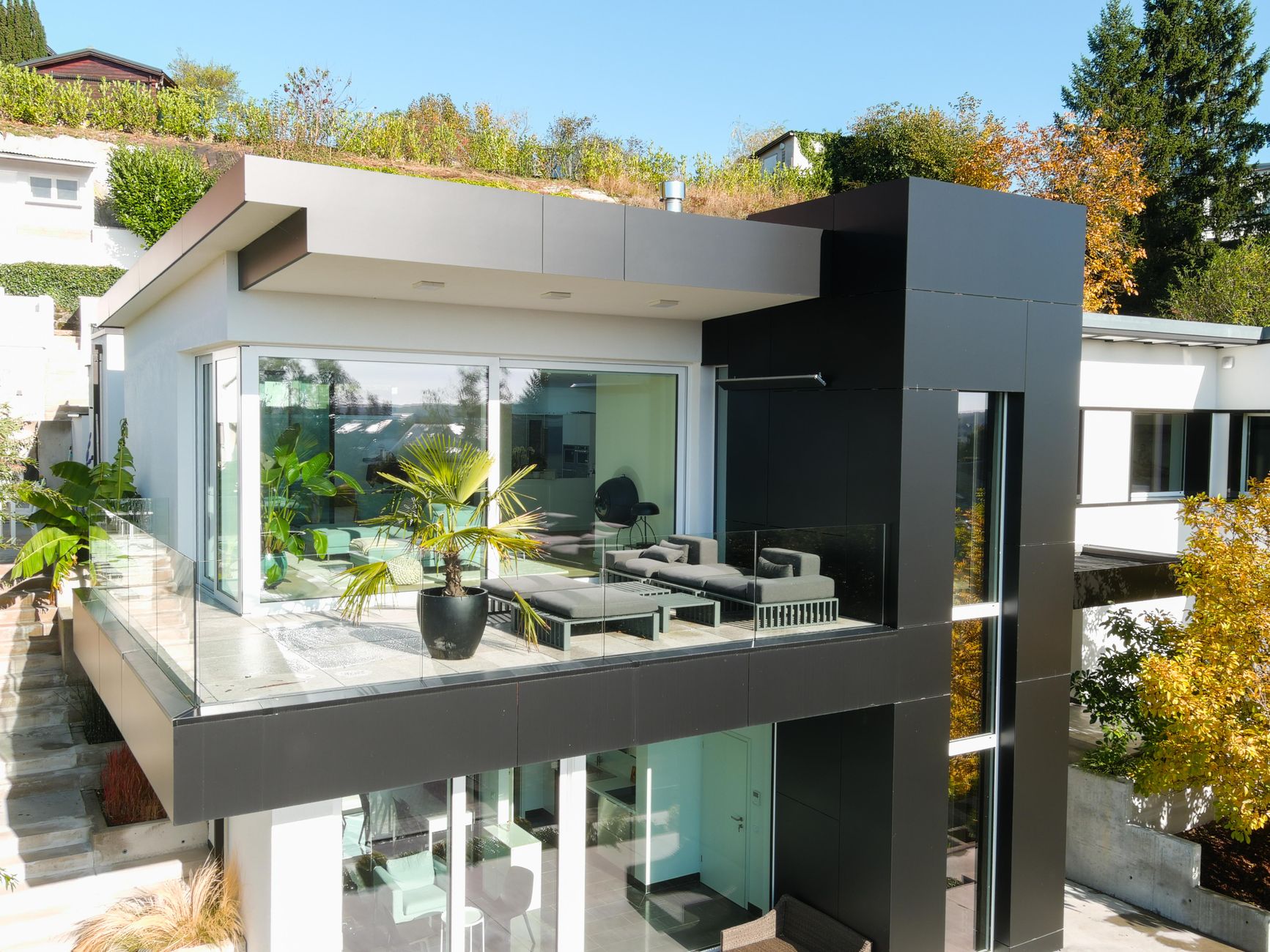 high end balcony design for modern homes Contemporary house featuring glass balcony, lush plants, and stylish design.