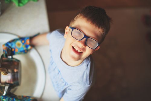 Free Cheerful child with glasses fogged up, smiling in a kitchen setting. Stock Photo