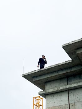 Construction worker standing on a building edge, showcasing urban development.