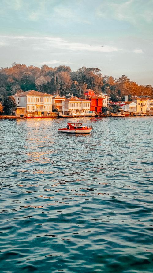 Free A peaceful lake view with colorful houses along the shoreline and a small boat in Turkey's serene landscape. Stock Photo