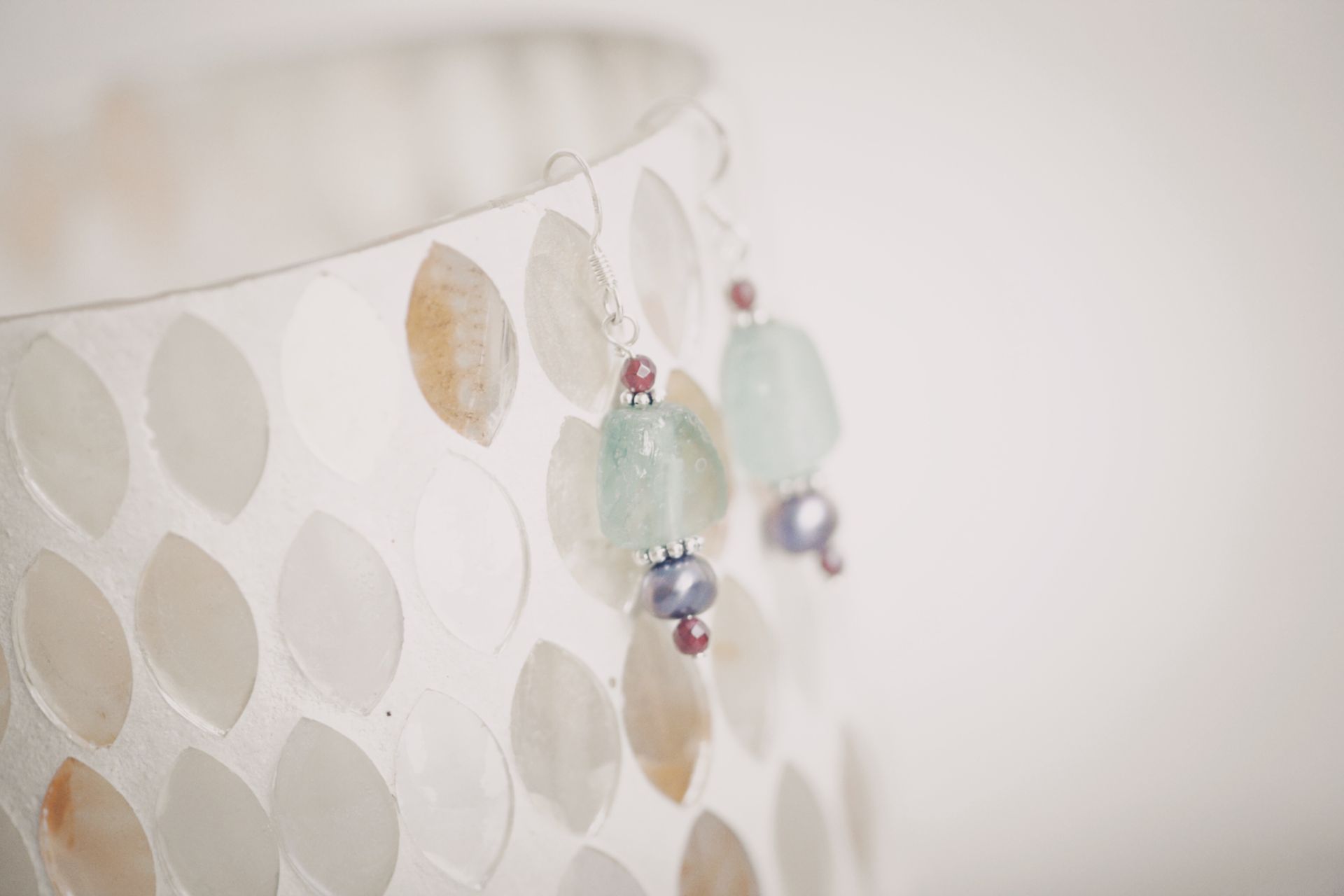 Close-up image of stylish beaded earrings with aquamarine and pearl accents.