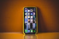 智能手机的特写镜头中，黄色外壳上显示着各种应用程序图标，并在表面形成反射