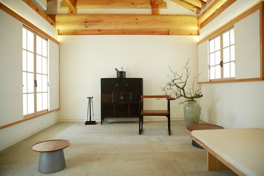 A serene Japanese-inspired room with minimalist furniture and natural wooden beams. — photo by 준섭 윤
