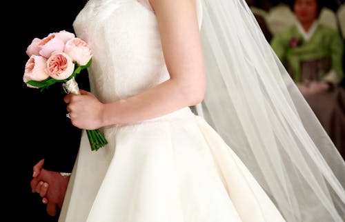 A Bride in White Wedding Gown Holding a Bouquet of Flowers